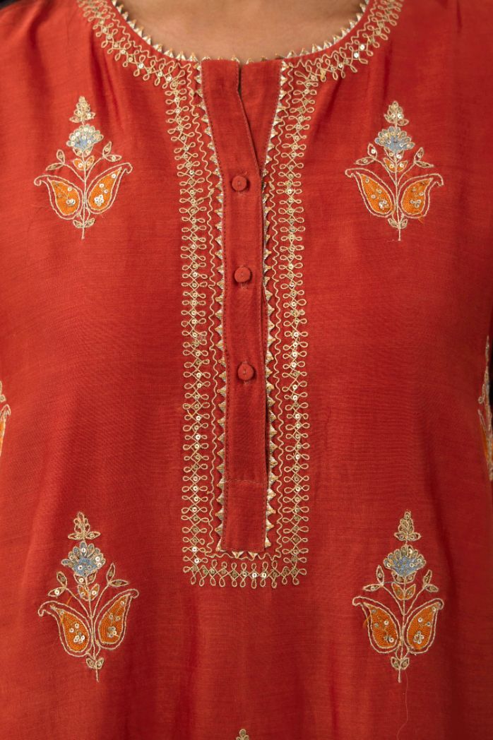 Rust silk chanderi A-line short kurta set with dori and contrast silk thread embroidery, highlighted with gold sequins work.