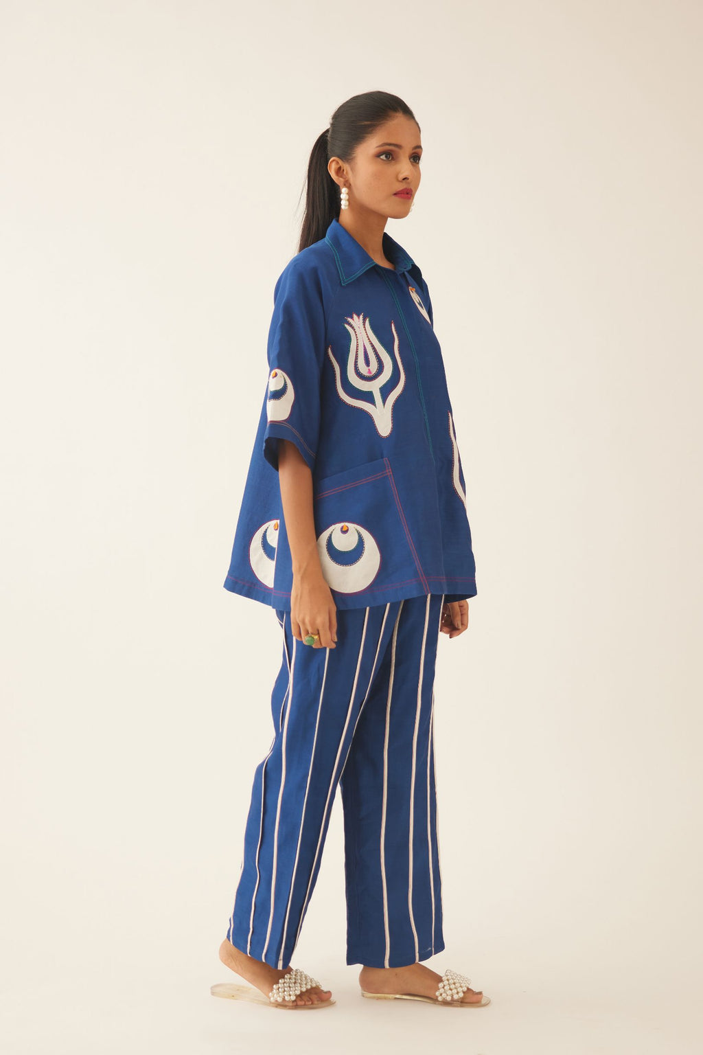 Blue silk chanderi short top with cotton appliqué boota, highlighted with kantha multi colored thread work, paired with blue silk chanderi straight pants with vertical off white piping detail.