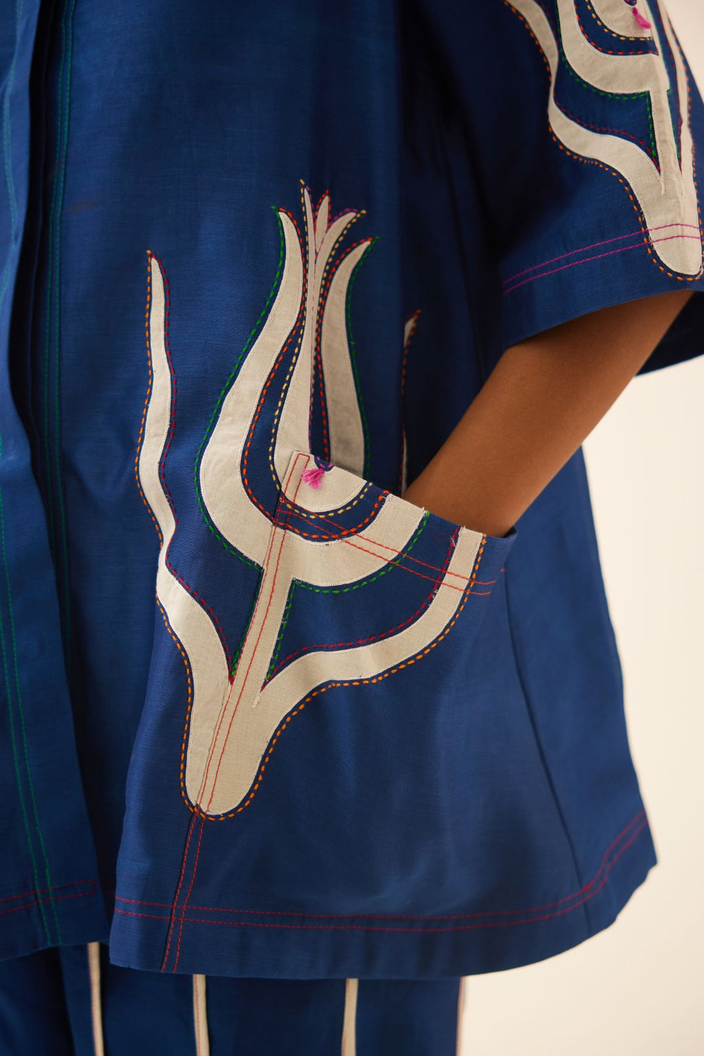 Blue silk chanderi short top with cotton appliqué boota, highlighted with kantha multi colored thread work, paired with blue silk chanderi straight pants with vertical off white piping detail.