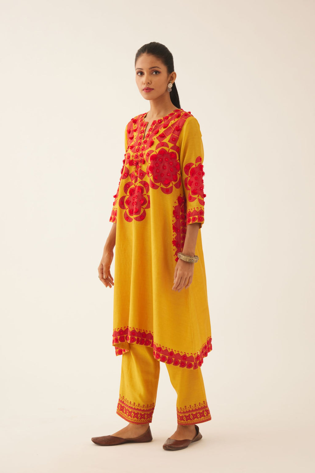 Golden yellow silk chanderi A-line kurta set, highlighted with contrast applique, tassels and sequins.