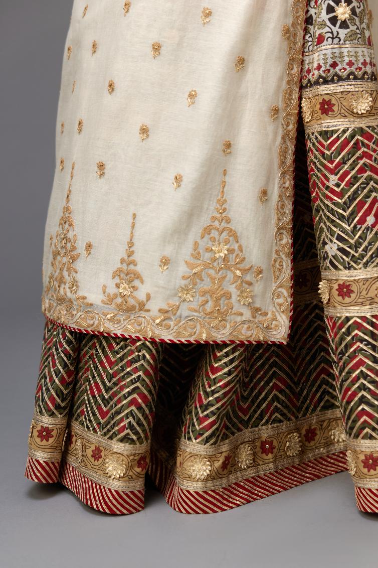 Off white cotton chanderi straight kurta with dori and gota embroidery, detailed with all-over delicate aari embroidery buties, paired with Silk chanderi hand block printed lehenga with herringbone gota embroidery at hem.