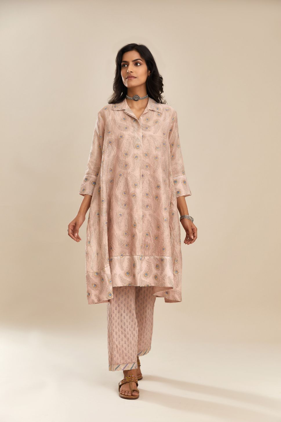 Pink hand block printed silk chanderi  A-line short shirt kurta with silk fabric detailing at hem and front placket that ends with a box pleat, paired with  pink hand block printed straight pants with striped fabric attached at bottom.