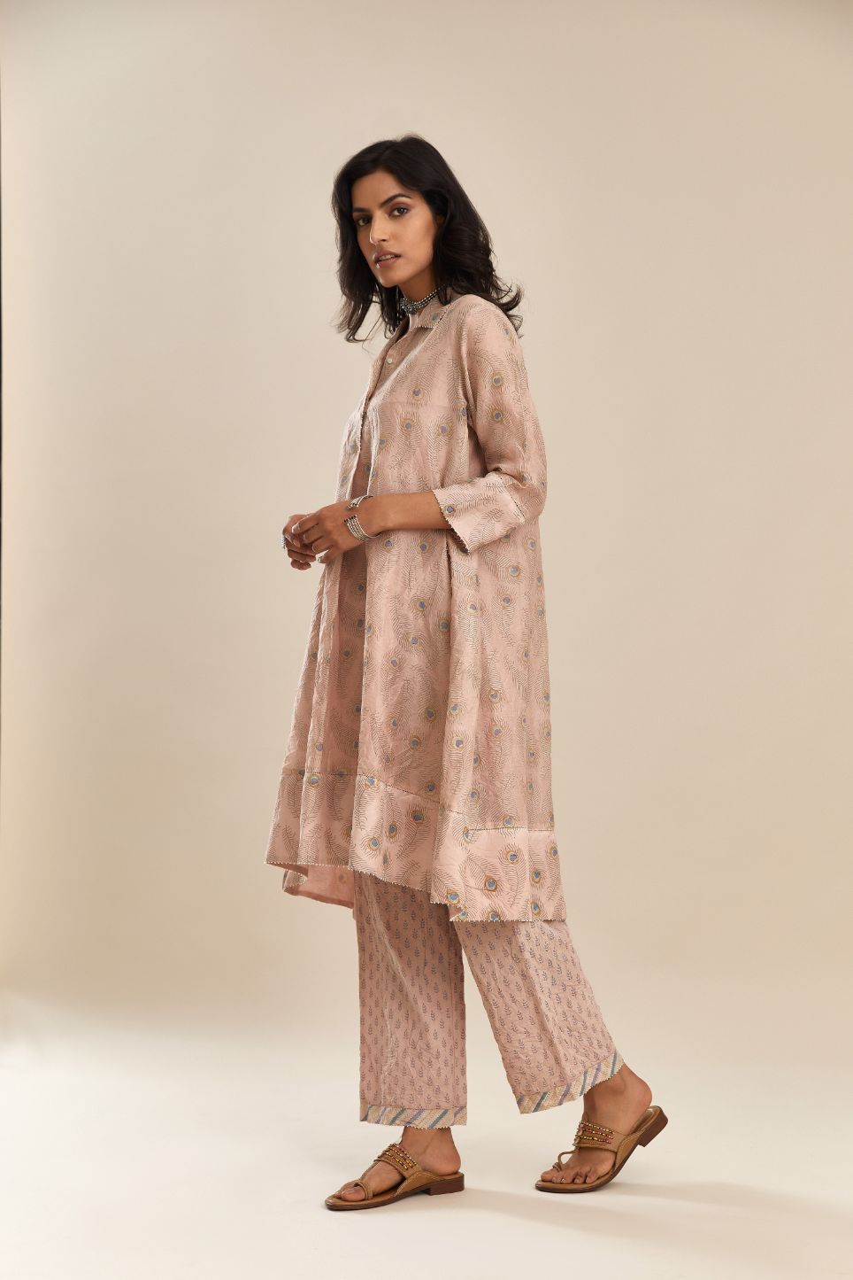 Pink hand block printed silk chanderi  A-line short shirt kurta with silk fabric detailing at hem and front placket that ends with a box pleat, paired with  pink hand block printed straight pants with striped fabric attached at bottom.