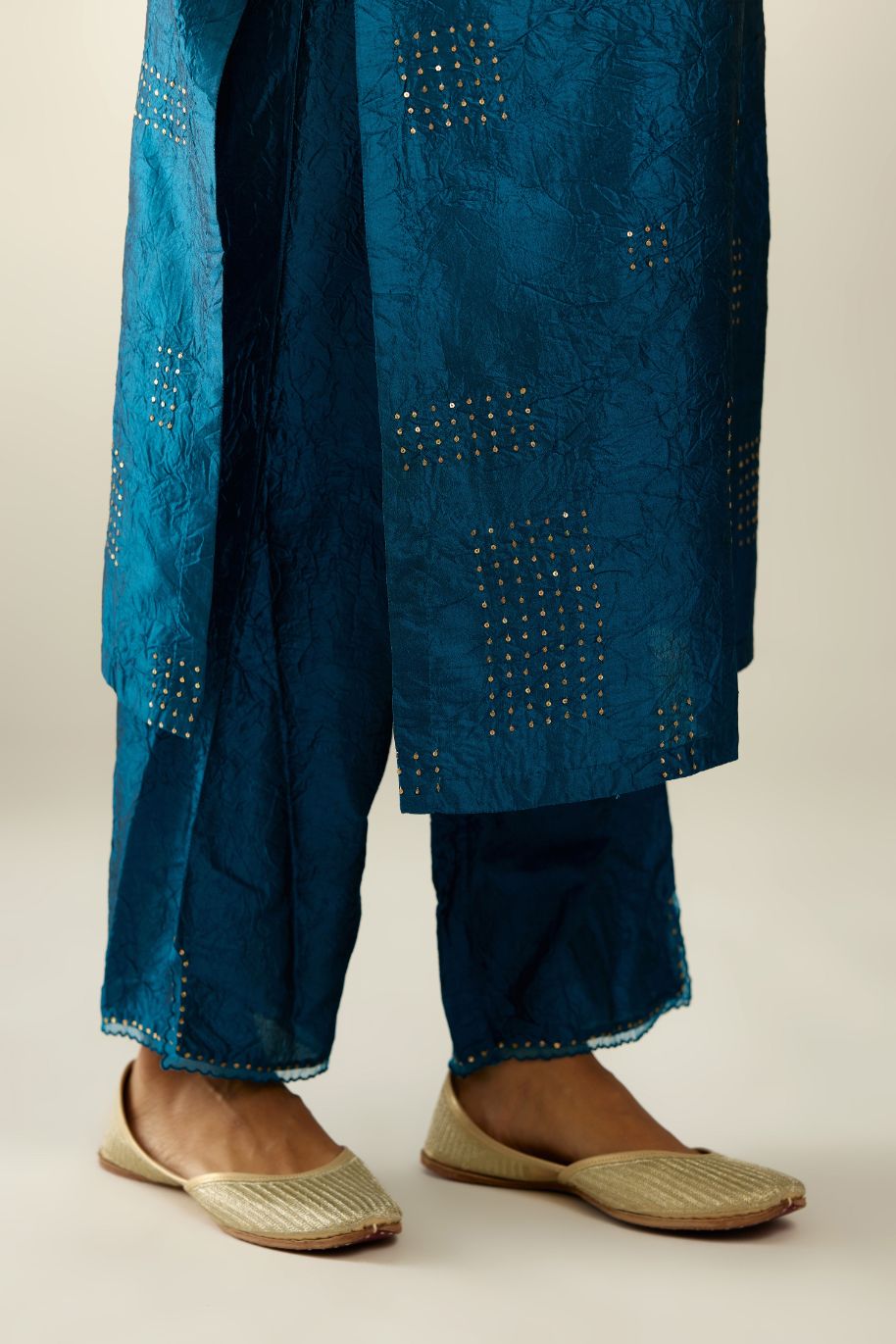 Dark teal hand crushed silk straight kurta, highlighted with all-over gold sequins rectangles, paired with  dark teal hand crushed silk straight pants with scalloped and embroidered organza at edges and detailed with a single line of sequins at hem