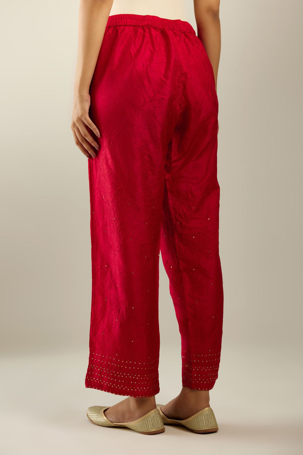 Red hand crushed pure silk straight pants with gold sequins at hem in horizontal lines formation and side pockets.