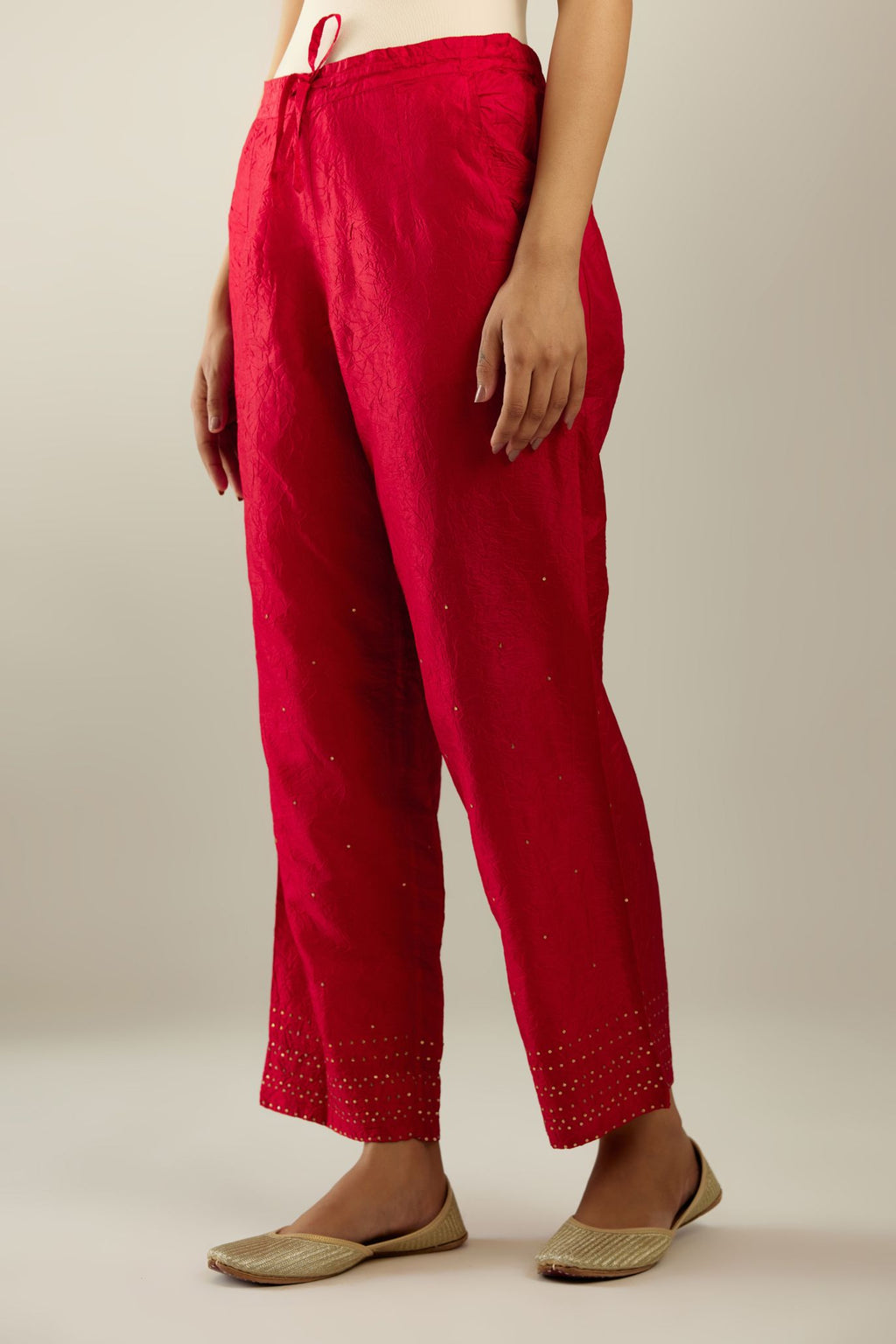 Red hand crushed pure silk straight pants with gold sequins at hem in horizontal lines formation and side pockets.