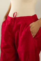 Red hand crushed pure silk straight pants with gold sequins at hem in horizontal lines formation and side pockets.