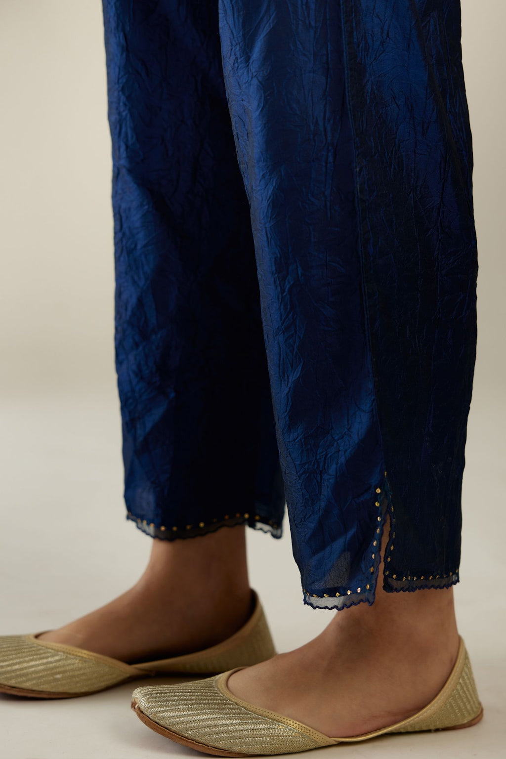 Navy blue hand crushed silk straight pants with scalloped and embroidered organza at edges and detailed with a single line of sequins at hem.