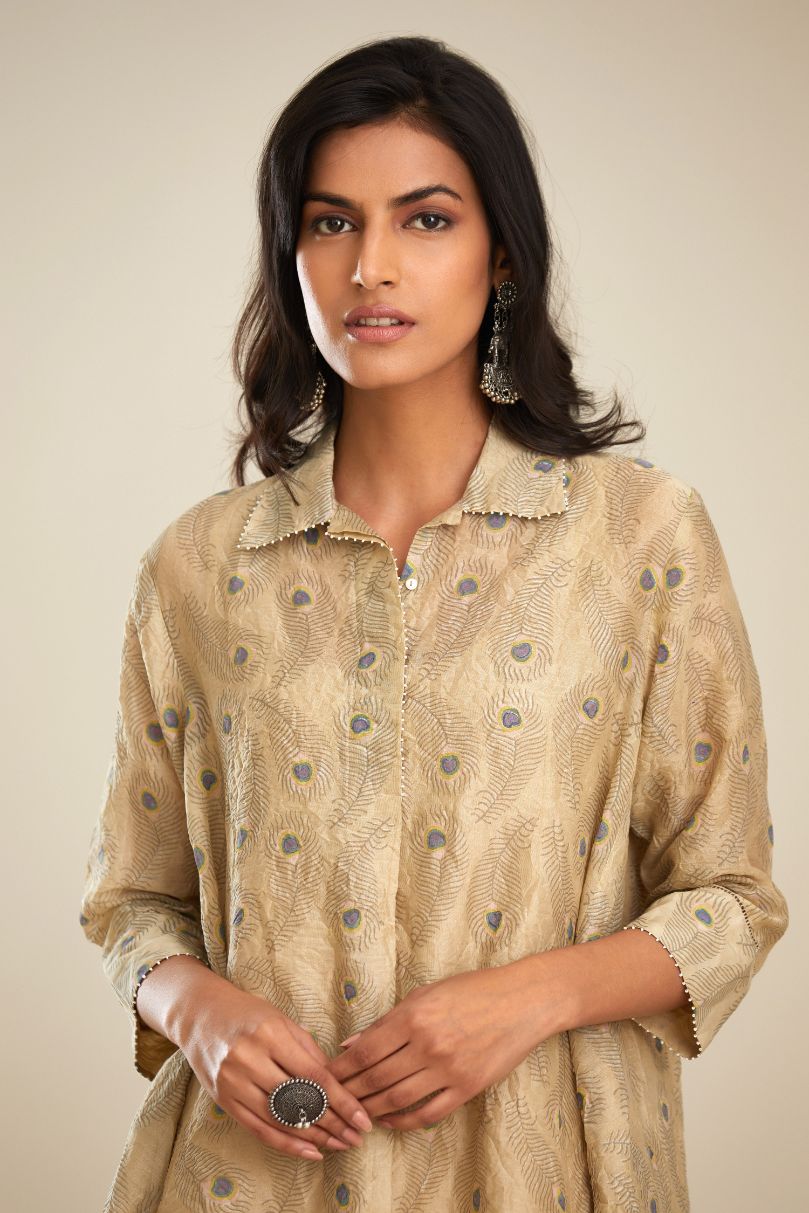 Beige hand block printed silk chanderi  A-line short shirt kurta with silk fabric detailing at hem and front placket that ends with a box pleat, paired with beige hand block printed straight pants with striped fabric attached at bottom.