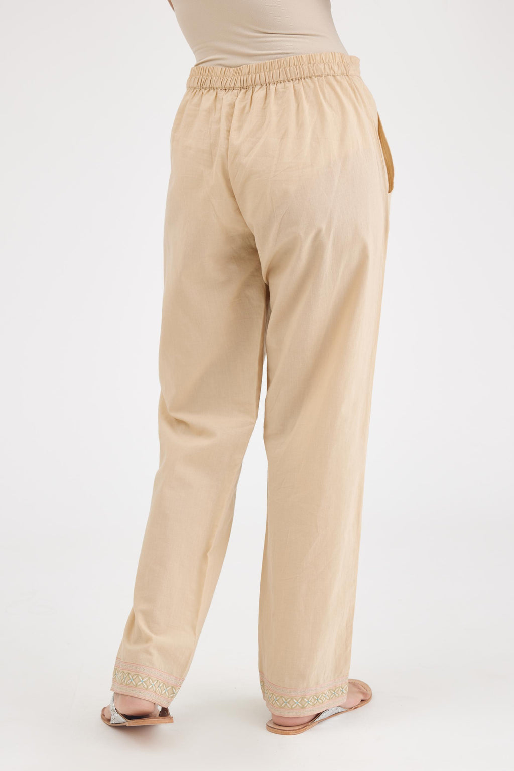 Beige cotton straight pants with multi colored thread embroidery, highlighted with silver zari embroidery at bottom hem