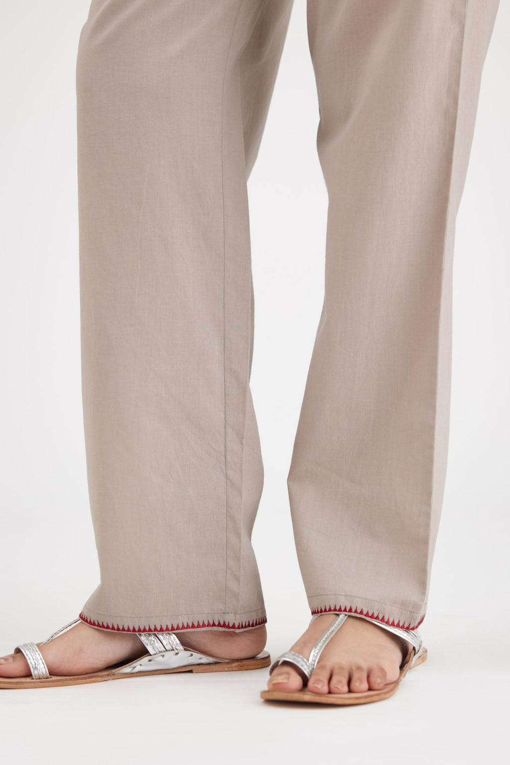 Grey cotton straight pants with contrasting thread embroidery at hem.