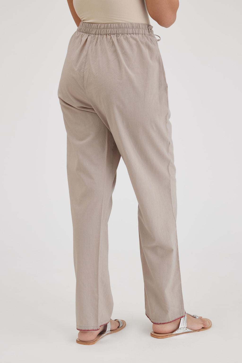 Grey cotton straight pants with contrasting thread embroidery at hem.