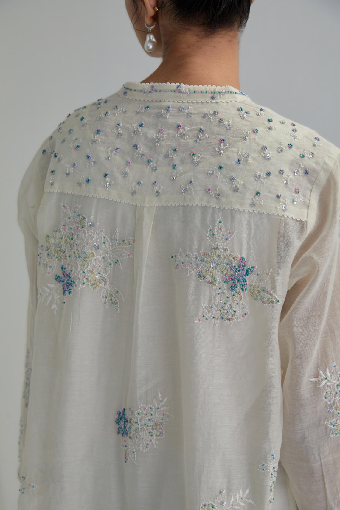 Off white cotton Chanderi top with all-over delicate embroidered blue & beige hand block printed applique flowers, highlighted with sequins and multi coloured beads.