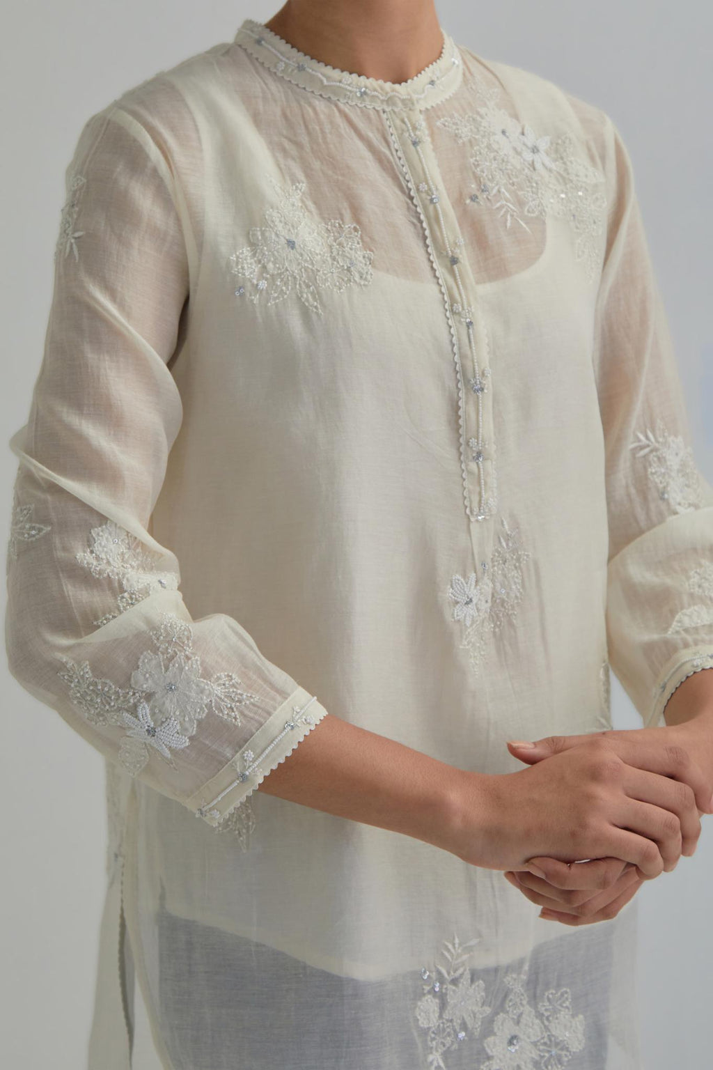 Off white cotton Chanderi top with all-over delicate embroidered applique flowers, highlighted with sequins and beads.