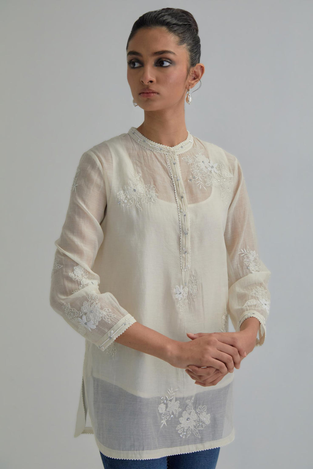 Off white cotton Chanderi top with all-over delicate embroidered applique flowers, highlighted with sequins and beads.