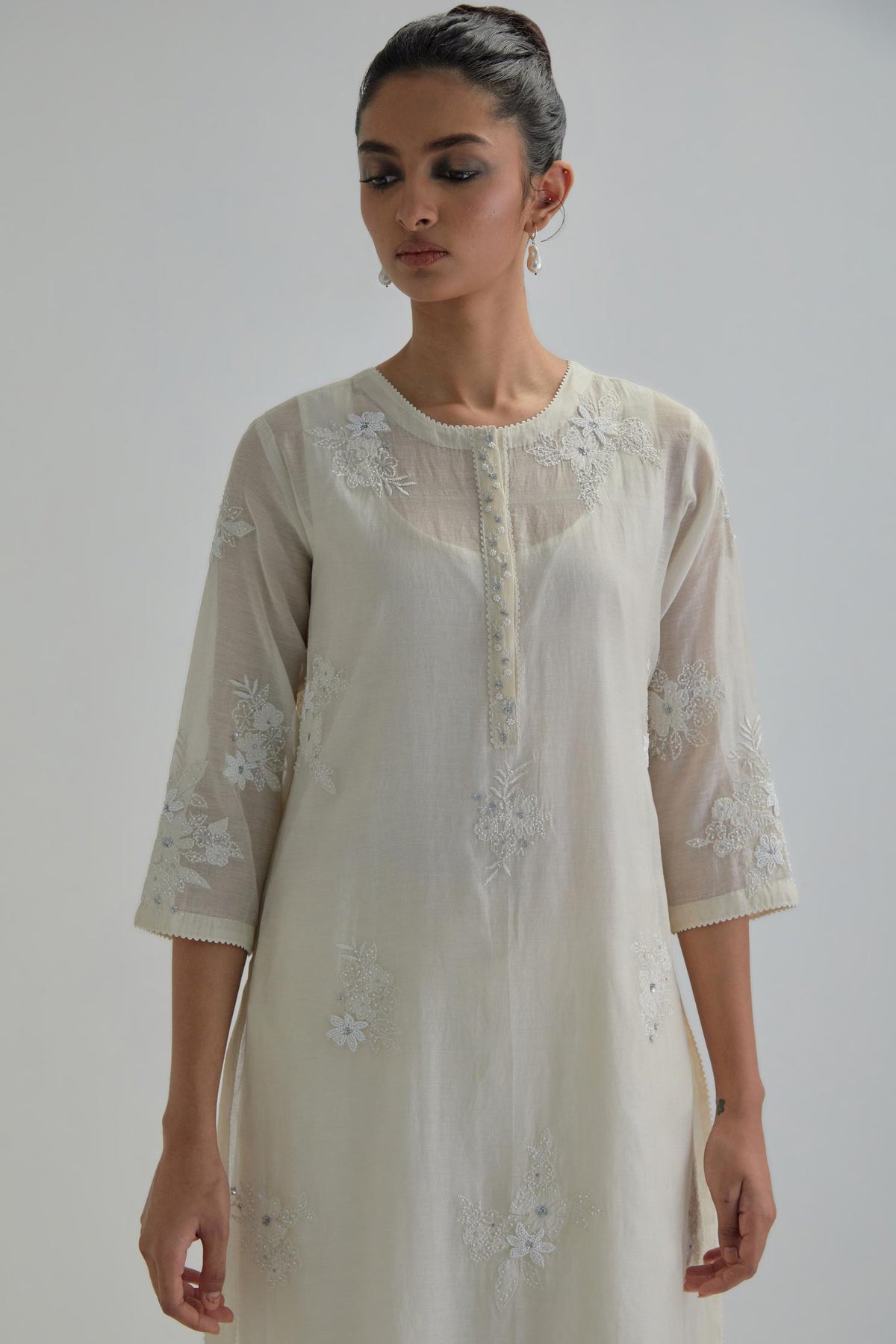 Off white straight short kurta set with all-over appliqué motifs, highlighted with sequins and beads.