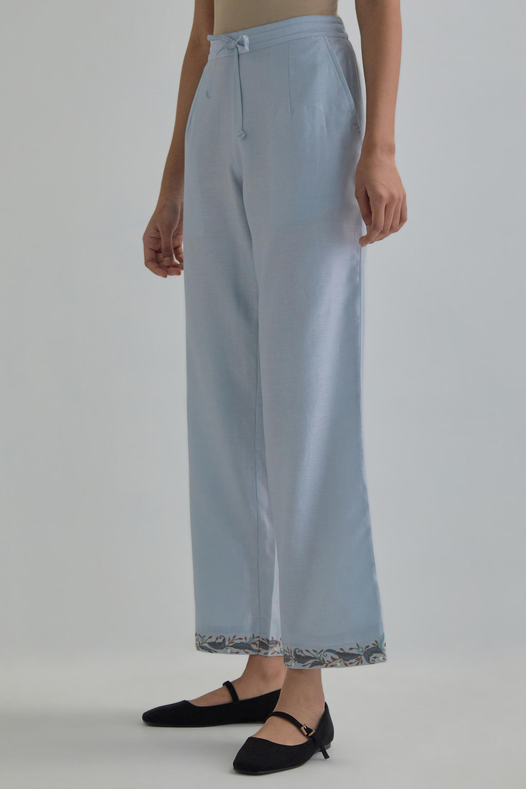 Blue silk Chanderi straight pants with earthy coloured Aari work at hem.