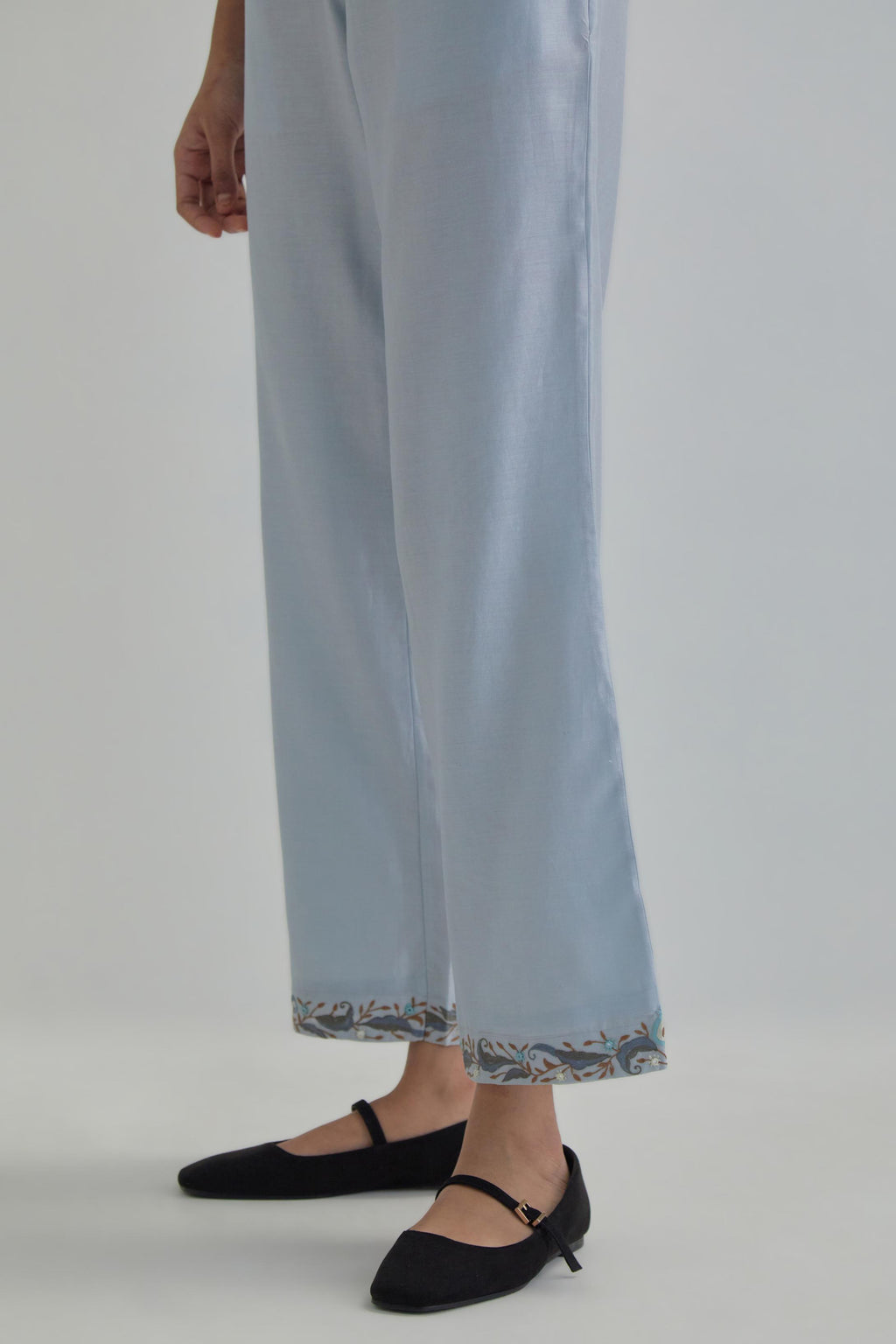 Blue silk Chanderi straight pants with earthy coloured Aari work at hem.