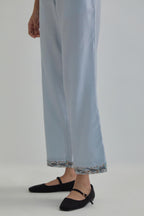 Blue silk Chanderi straight pants with earthy coloured Aari work at hem.