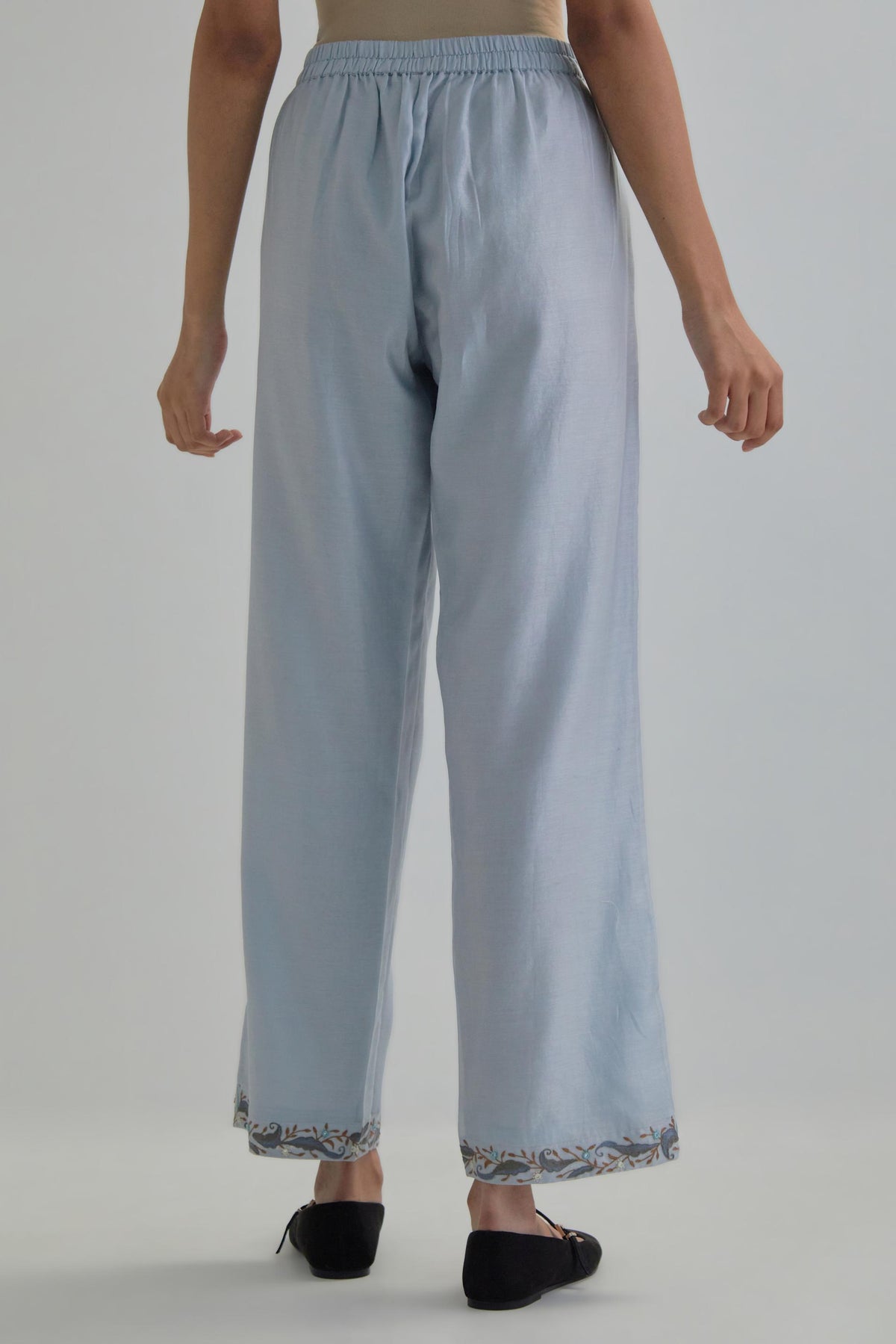 Blue silk Chanderi straight pants with earthy coloured Aari work at hem.