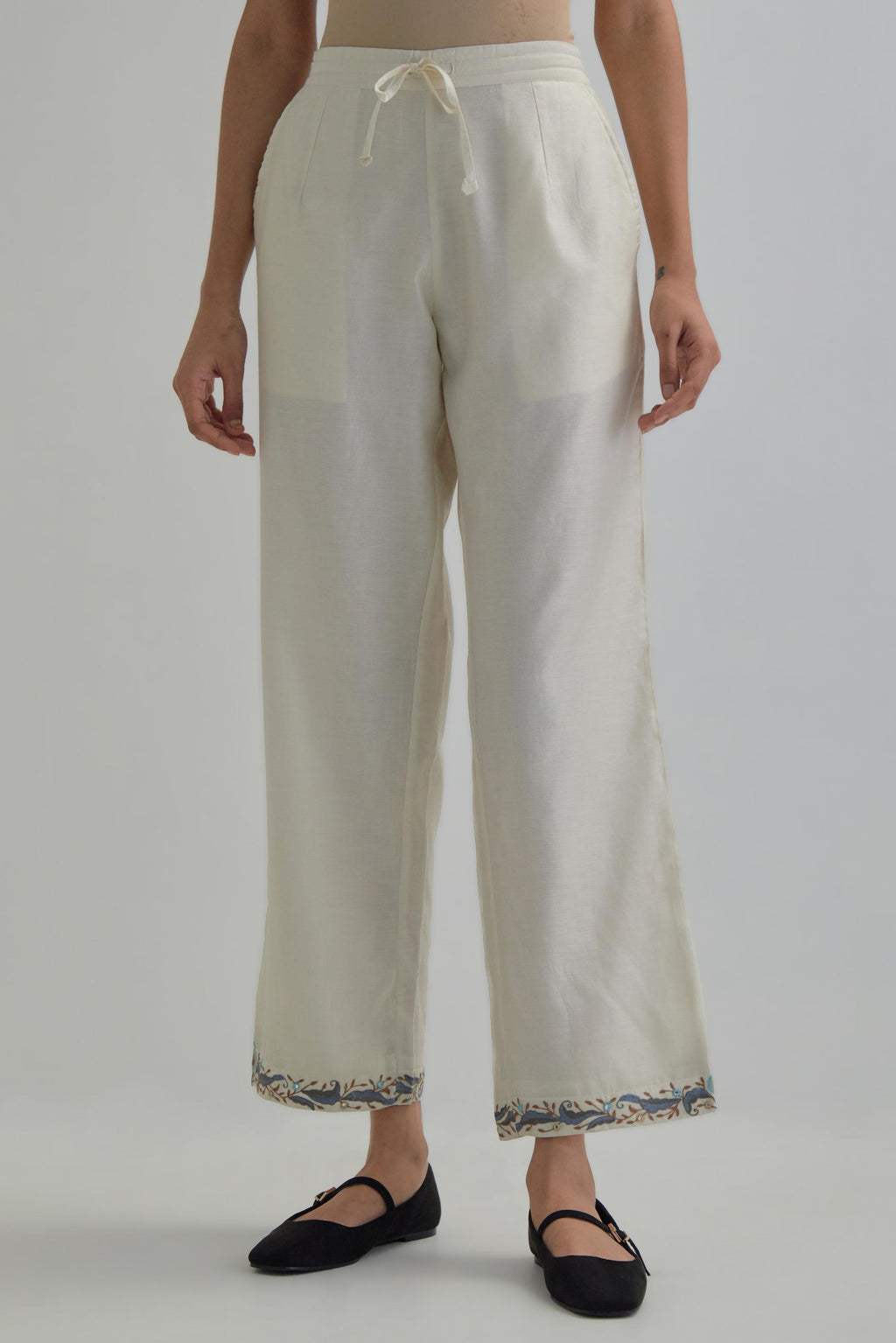 Off white silk Chanderi straight pants with earthy coloured Aari work at hem.