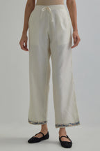 Off white silk Chanderi straight pants with earthy coloured Aari work at hem.
