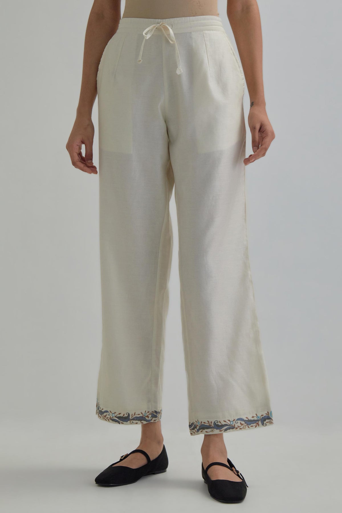 Off white silk Chanderi straight pants with earthy coloured Aari work at hem.