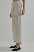 Off white silk Chanderi straight pants with earthy coloured Aari work at hem.