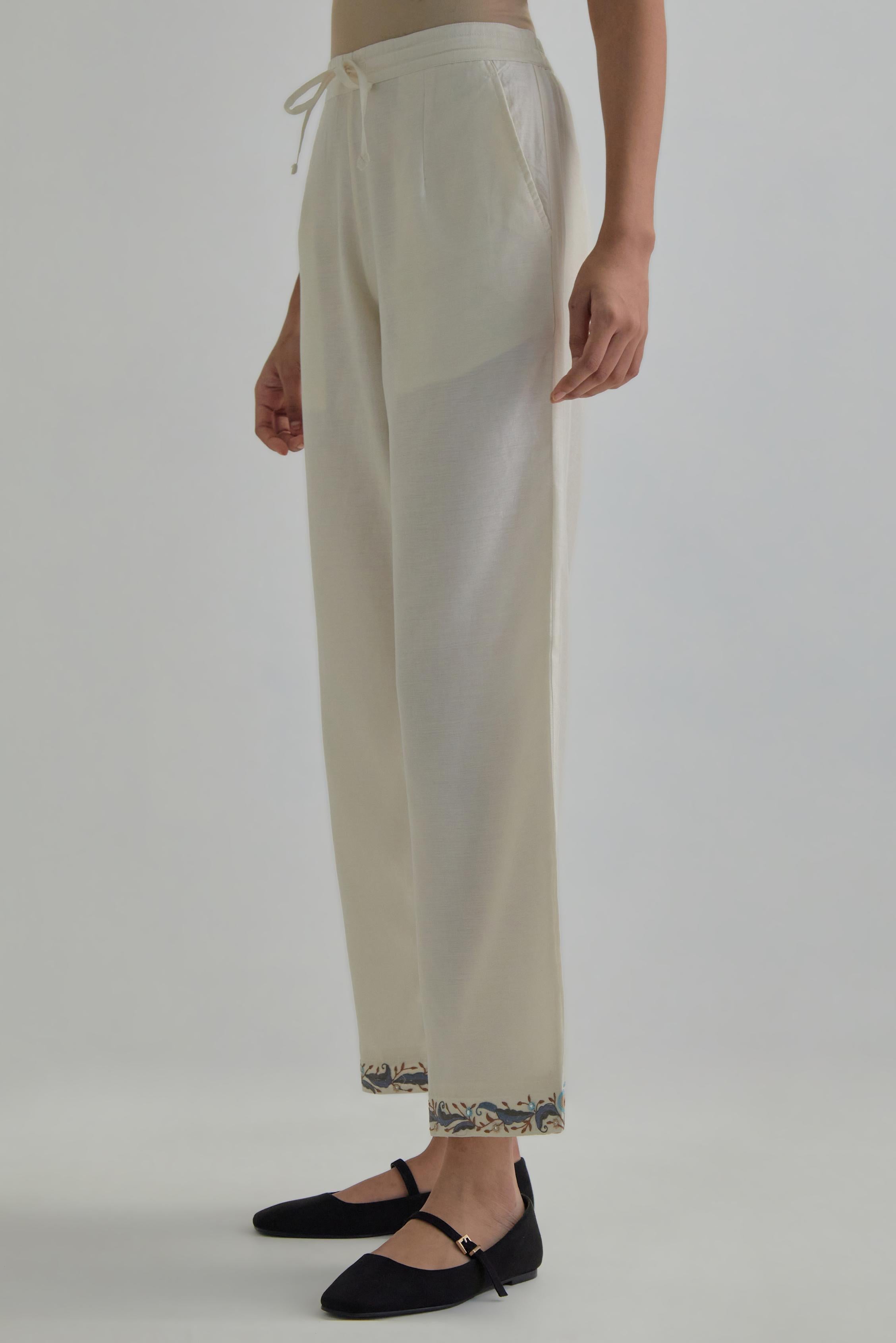 Off white silk Chanderi straight pants with earthy coloured Aari work at hem.