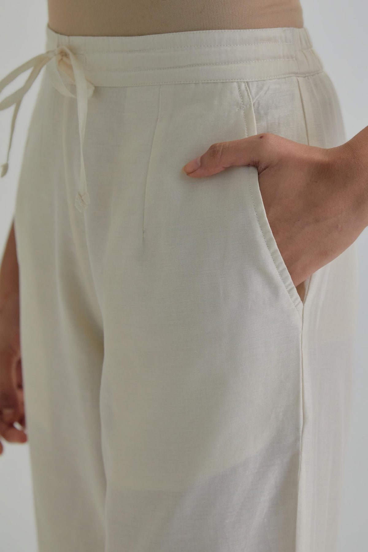 Off white silk Chanderi straight pants with earthy coloured Aari work at hem.