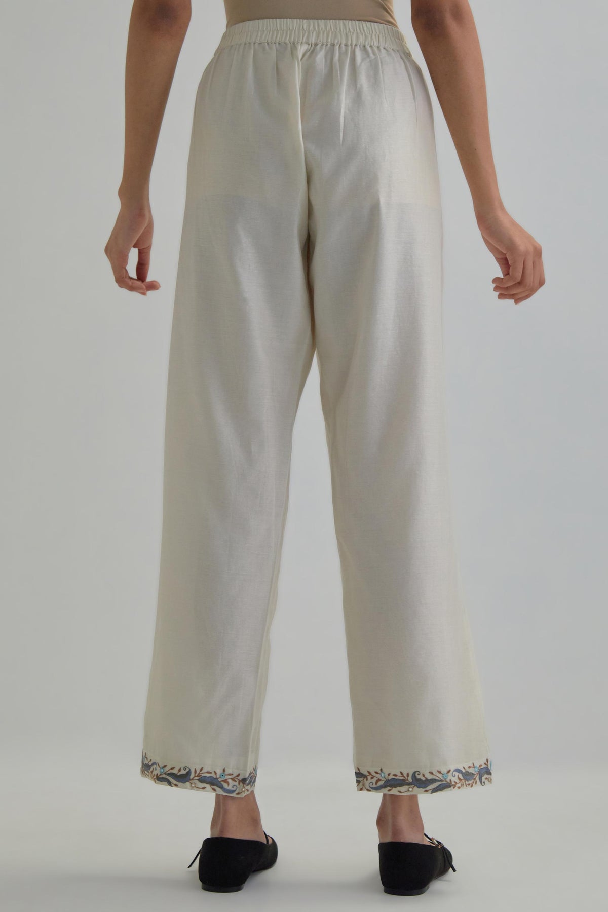 Off white silk Chanderi straight pants with earthy coloured Aari work at hem.