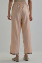 Pink silk Chanderi straight pants with earthy coloured Aari work at hem.