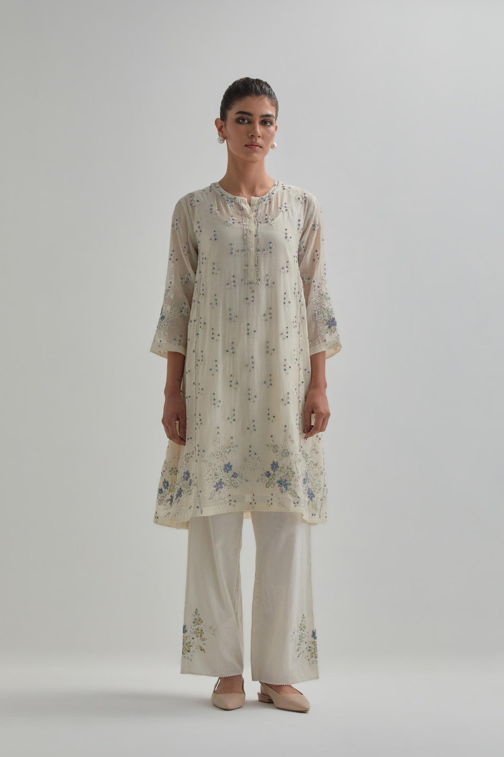 Off white cotton Chanderi short kalidar kurta set with all-over blue & beige hand block printed appliqué flowers, highlighted with sequins and multi coloured beads.