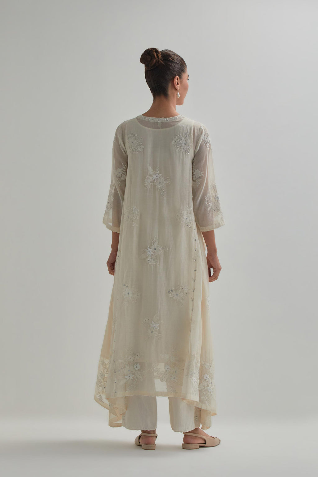 Off-white cotton Chanderi kurta set with asymmetric hem and all-over appliqué flowers, highlighted with sequins and beads.