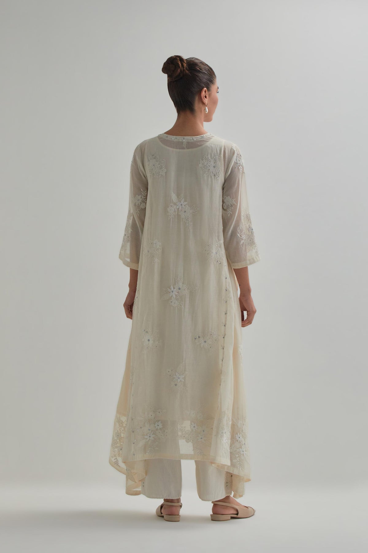 Off-white cotton Chanderi kurta set with asymmetric hem and all-over appliqué flowers, highlighted with sequins and beads.