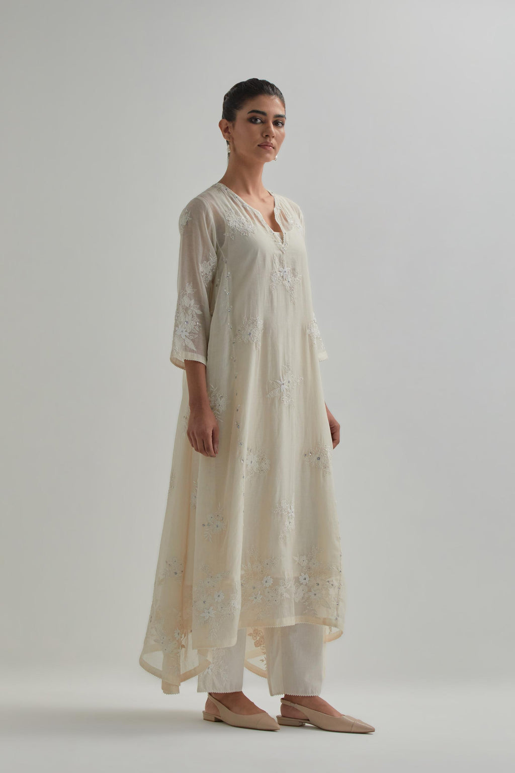Off-white cotton Chanderi kurta set with asymmetric hem and all-over appliqué flowers, highlighted with sequins and beads.