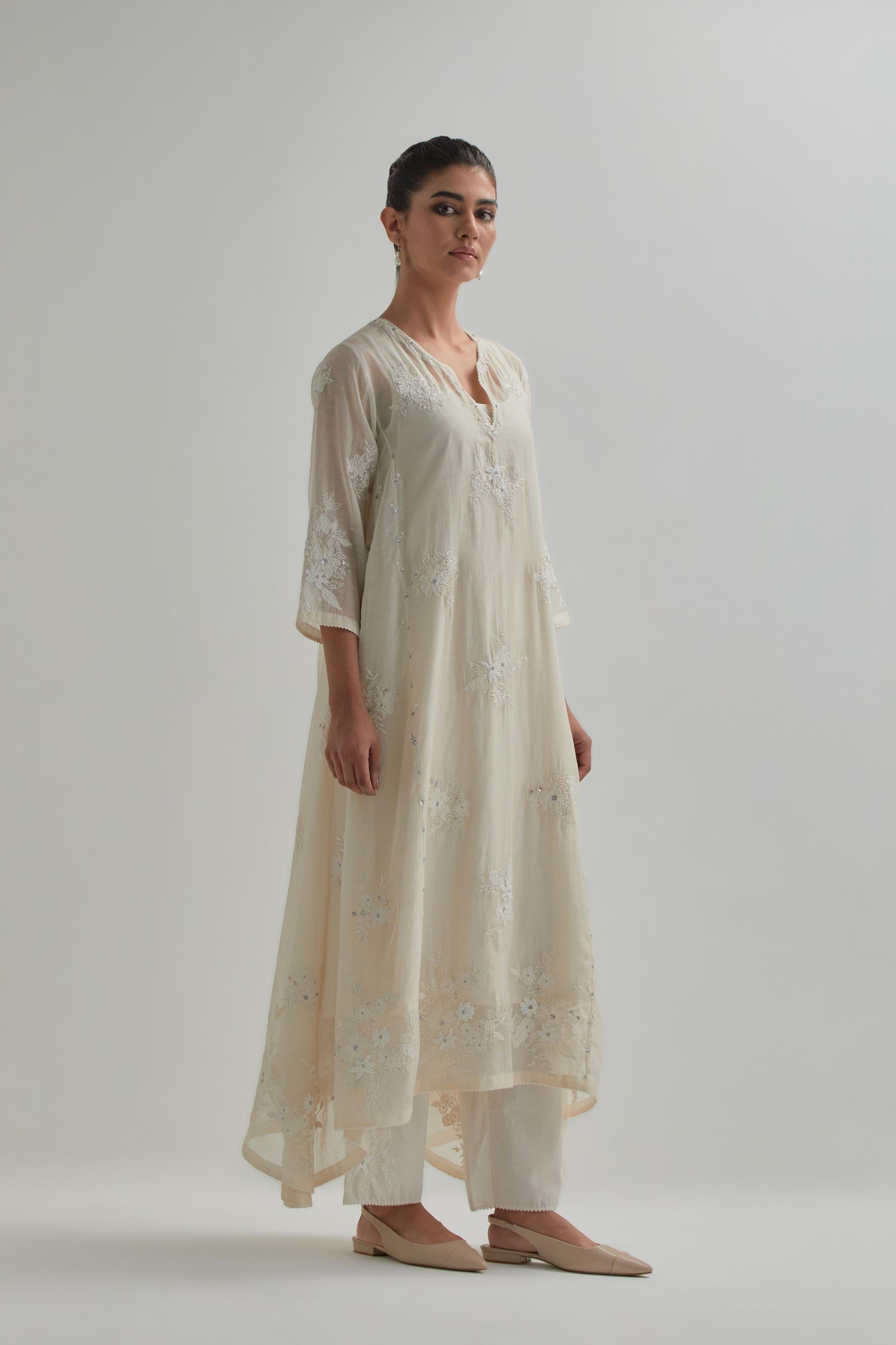 Off-white cotton Chanderi kurta set with asymmetric hem and all-over appliqué flowers, highlighted with sequins and beads.