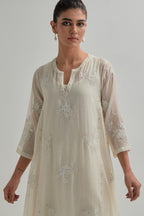 Off-white cotton Chanderi kurta set with asymmetric hem and all-over appliqué flowers, highlighted with sequins and beads.