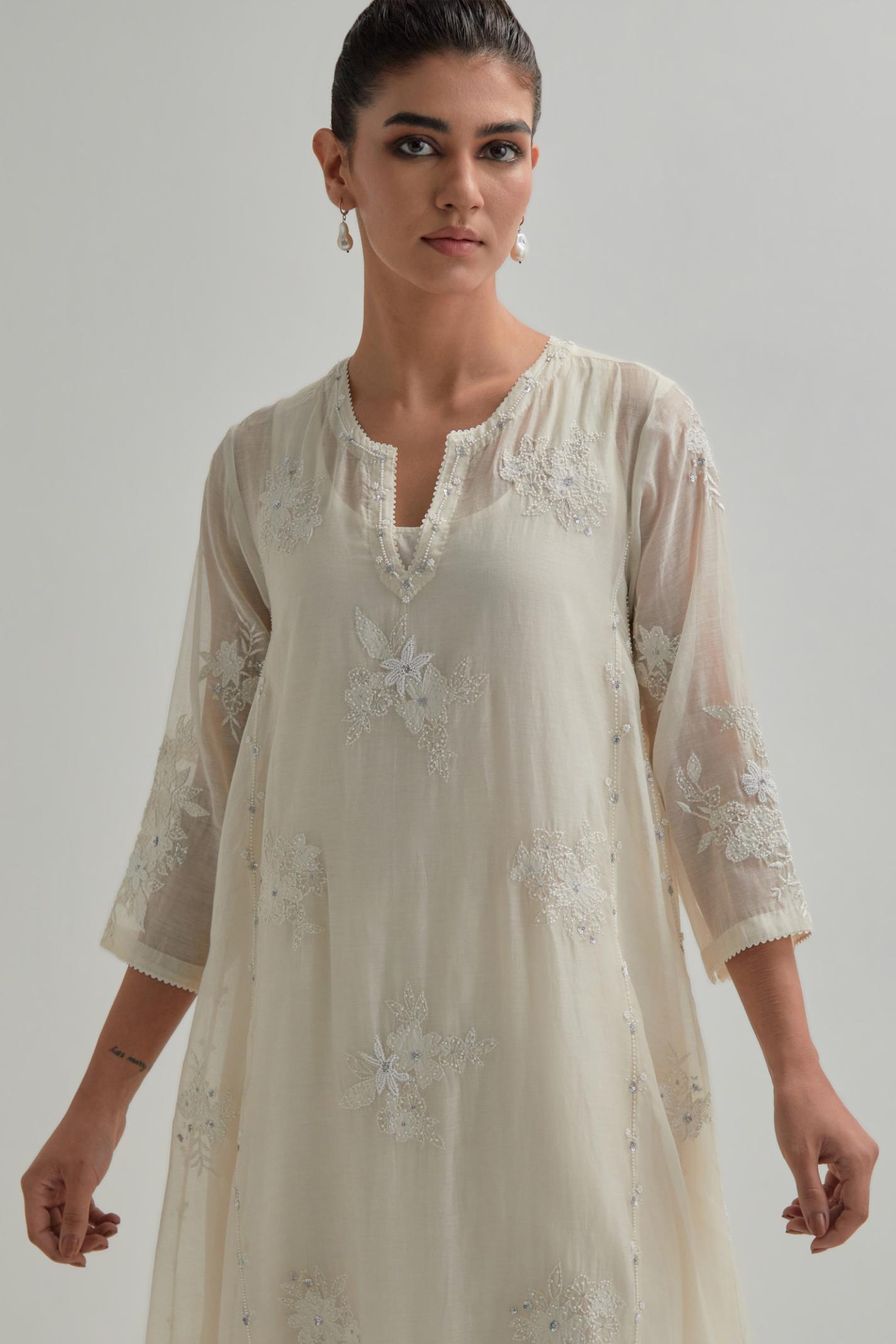 Off-white cotton Chanderi kurta set with asymmetric hem and all-over appliqué flowers, highlighted with sequins and beads.