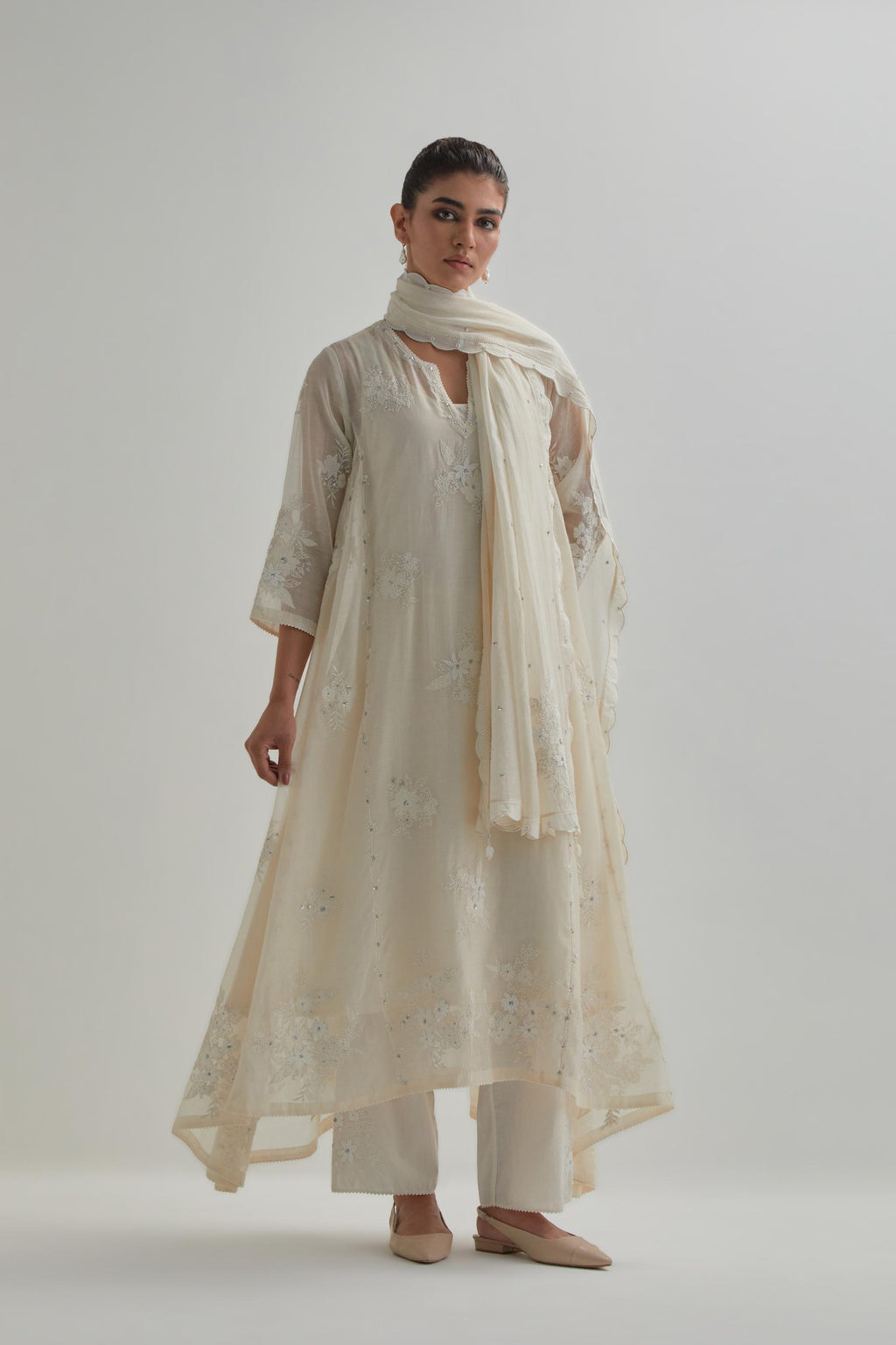 Off-white cotton Chanderi kurta set with asymmetric hem and all-over appliqué flowers, highlighted with sequins and beads.
