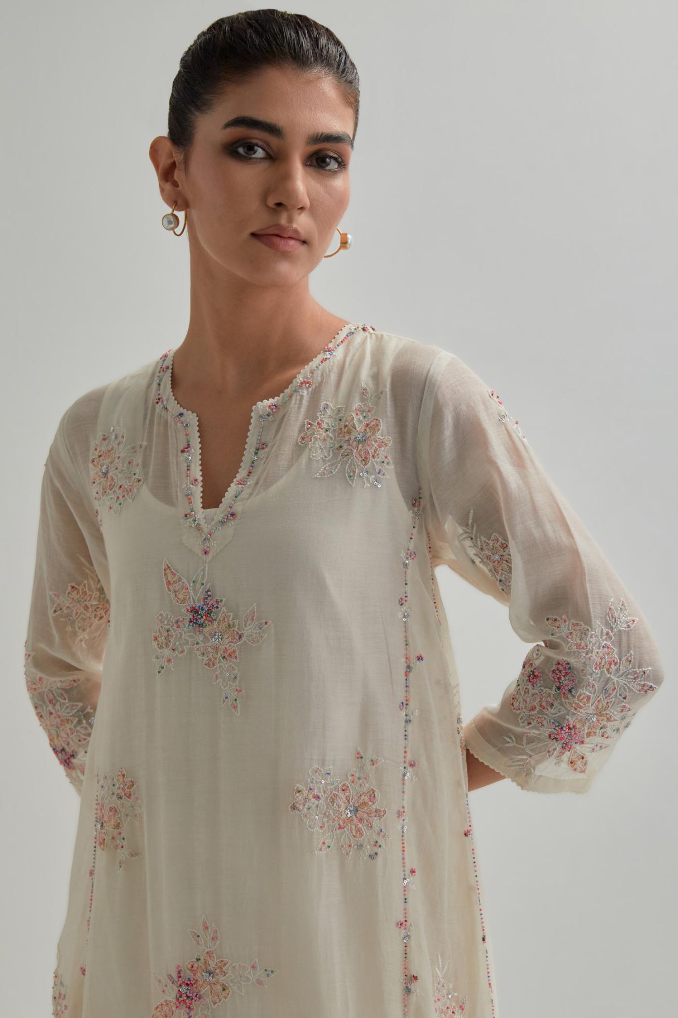 Off-white cotton Chanderi kurta set with asymmetric hem and all-over pink & beige hand block printed appliqué flowers.