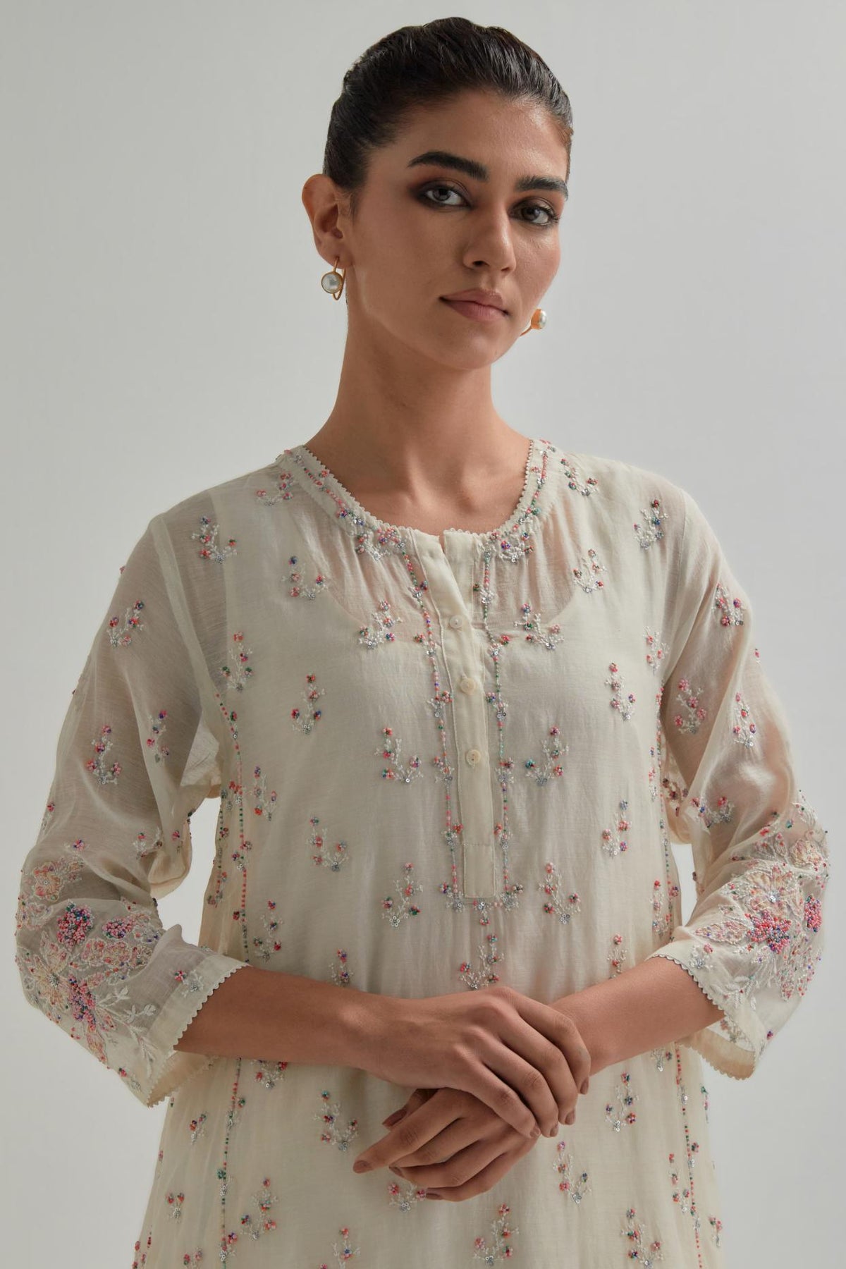 Off white cotton Chanderi short kalidar kurta set with all-over pink & beige hand block printed appliqué flowers, highlighted with sequins and multi coloured beads.