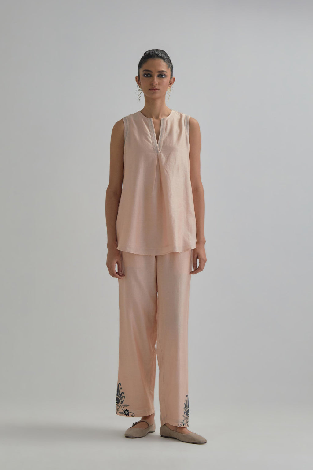 Pink short front open A-line jacket, fully embroidered with bold appliqué flowers, earthy-coloured Aari thread work and silk tassels, paired with Pink silk Chanderi straight pants with earthy coloured appliqué at hem.