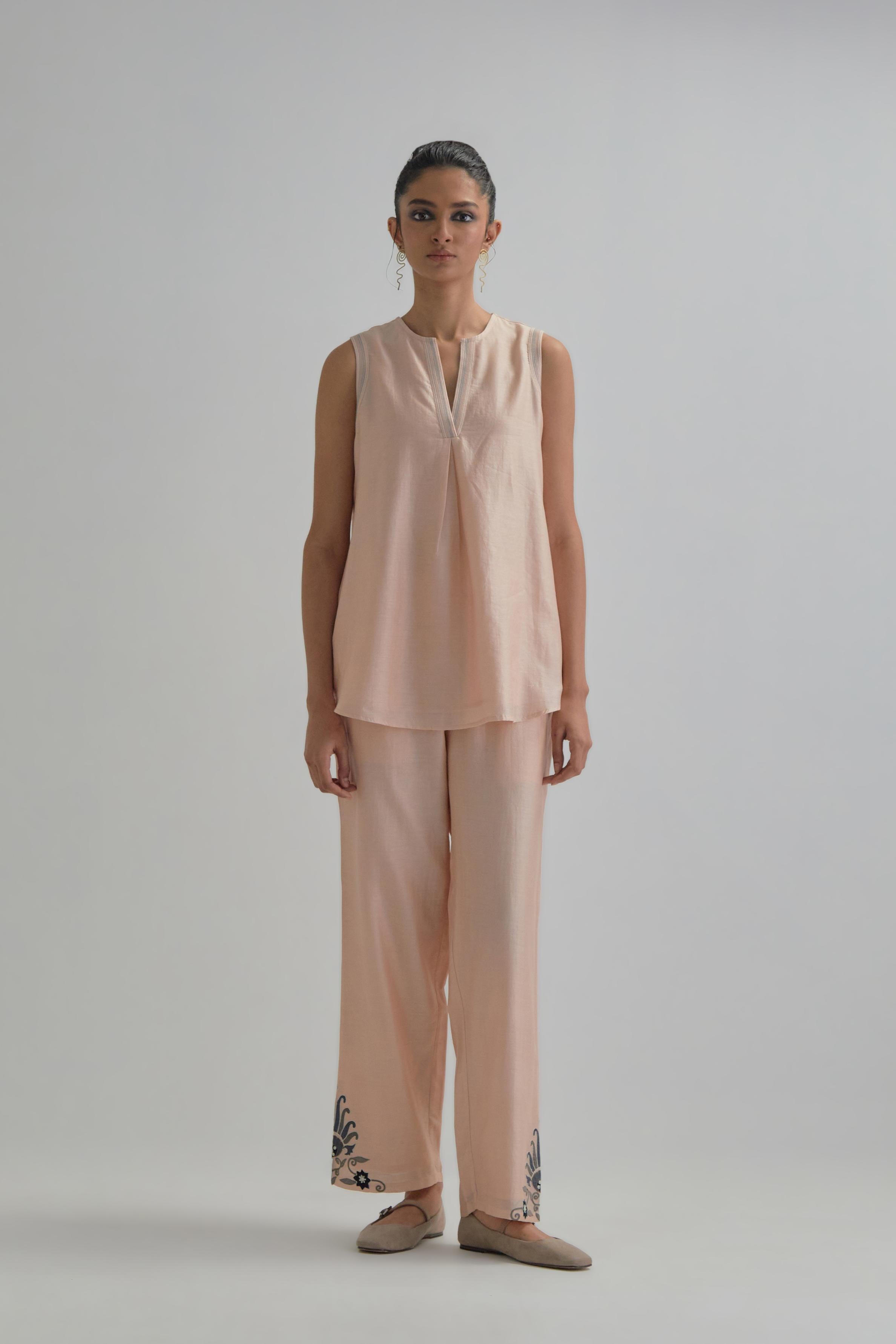 Pink short front open A-line jacket, fully embroidered with bold appliqué flowers, earthy-coloured Aari thread work and silk tassels, paired with Pink silk Chanderi straight pants with earthy coloured appliqué at hem.