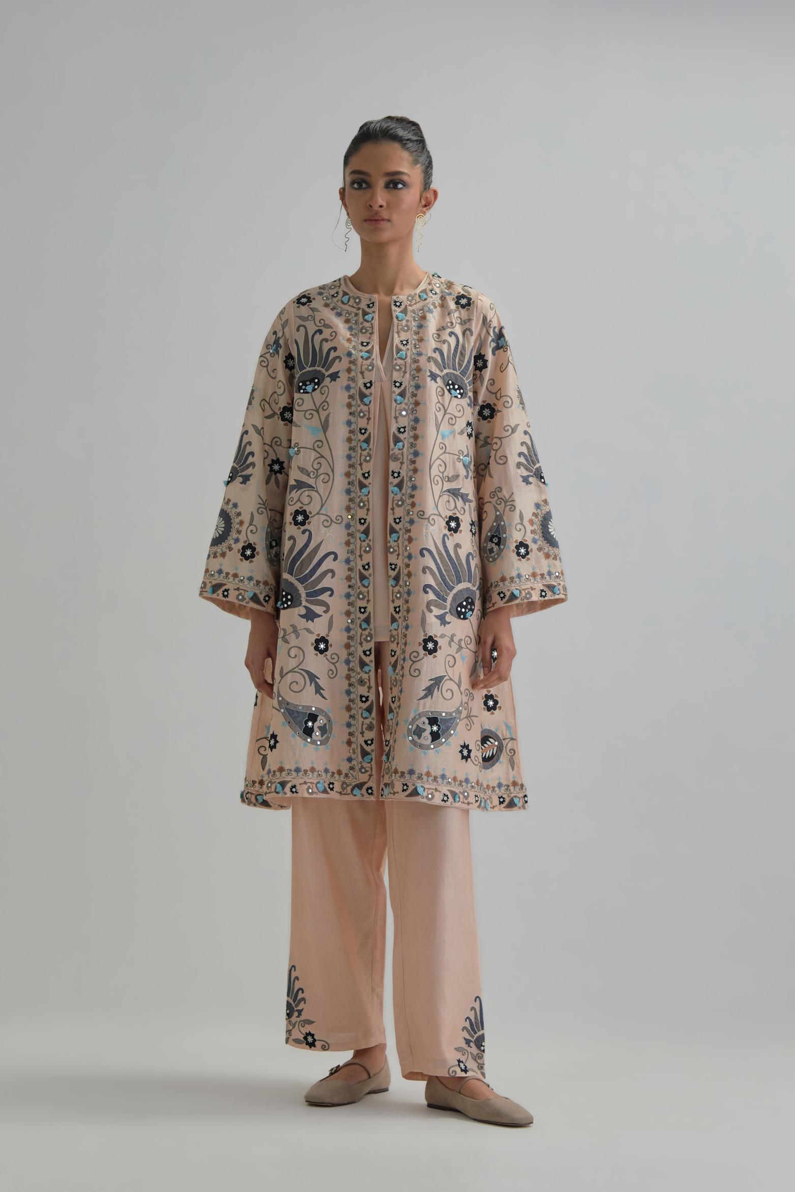 Pink short front open A-line jacket, fully embroidered with bold appliqué flowers, earthy-coloured Aari thread work and silk tassels, paired with Pink silk Chanderi straight pants with earthy coloured appliqué at hem.