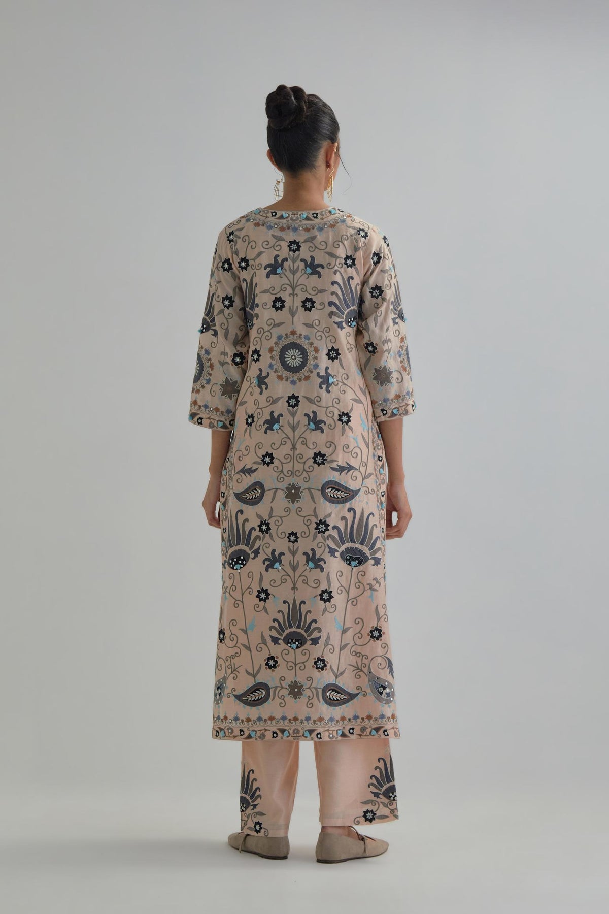 Pink straight kurta set, fully embroidered with bold appliqué flowers, earthy-coloured Aari thread work and silk tassels.