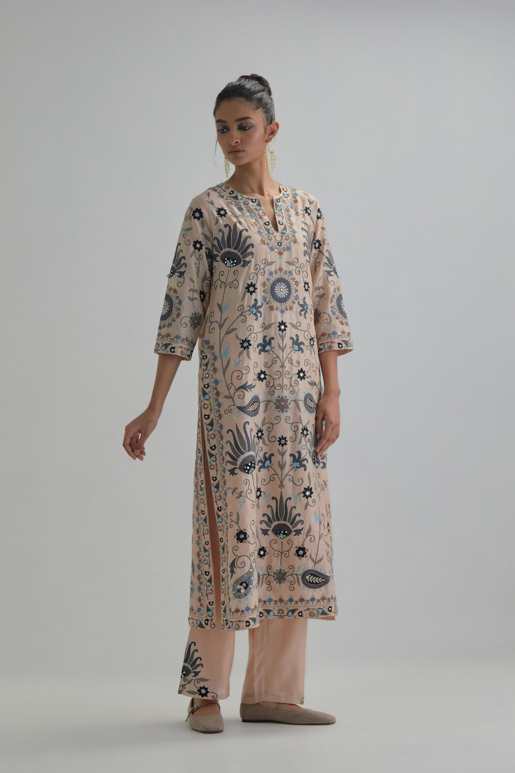 Pink straight kurta set, fully embroidered with bold appliqué flowers, earthy-coloured Aari thread work and silk tassels.