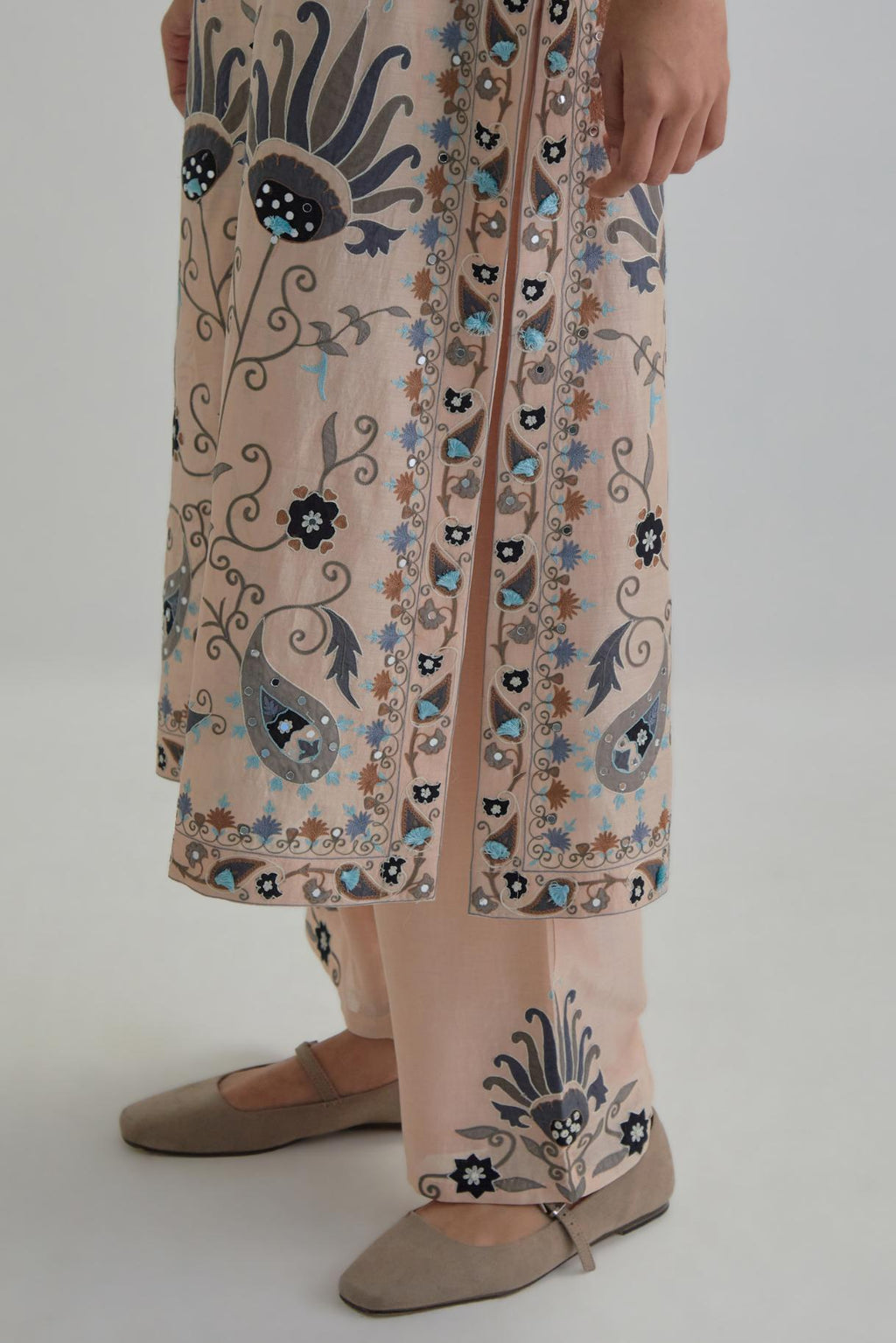 Pink straight kurta set, fully embroidered with bold appliqué flowers, earthy-coloured Aari thread work and silk tassels.