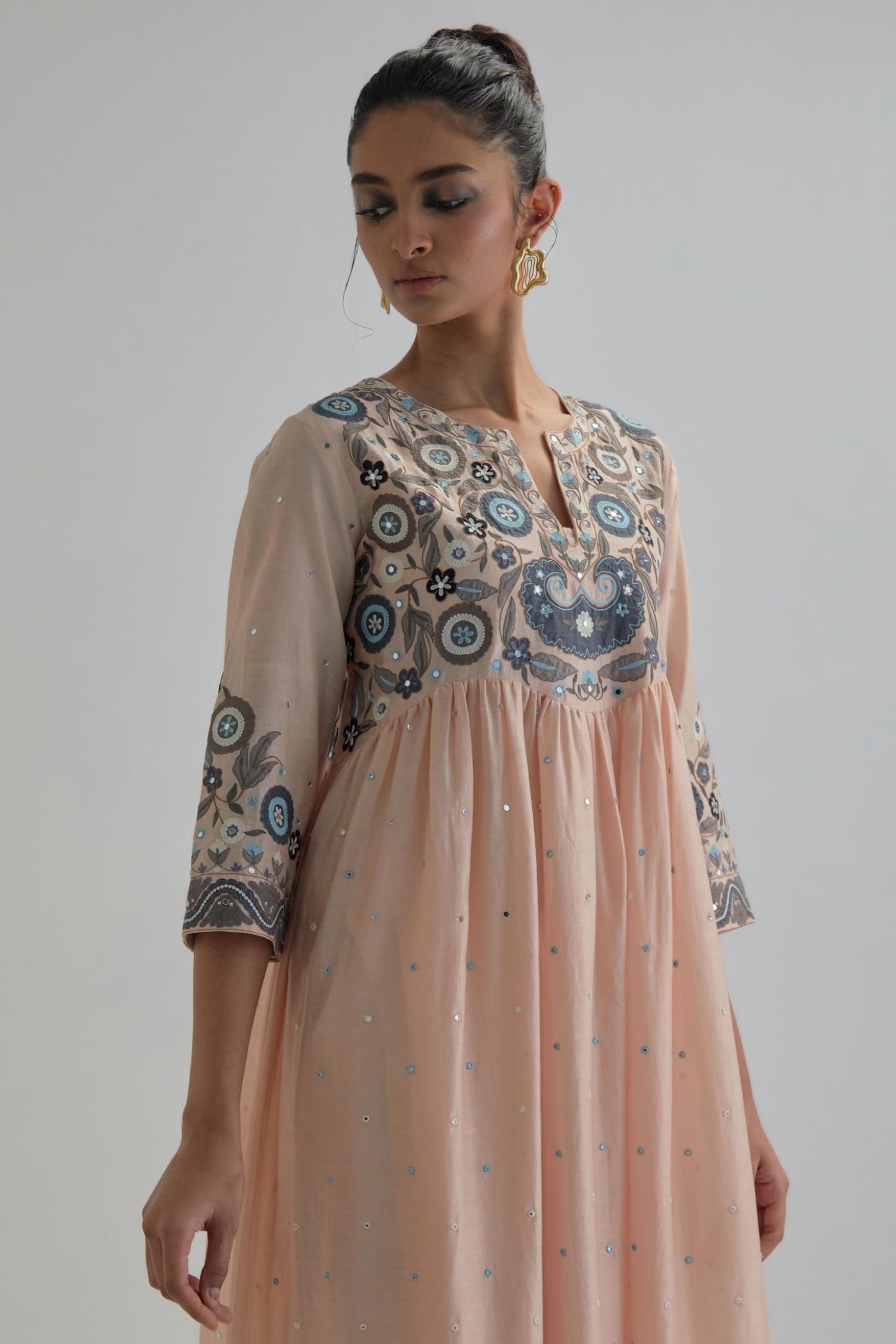 Pink silk Chanderi kurta-dress set with a wavy high-waist and fine gathers. The yoke is fully embroidered with earthy coloured circular appliqué and Aari thread work.