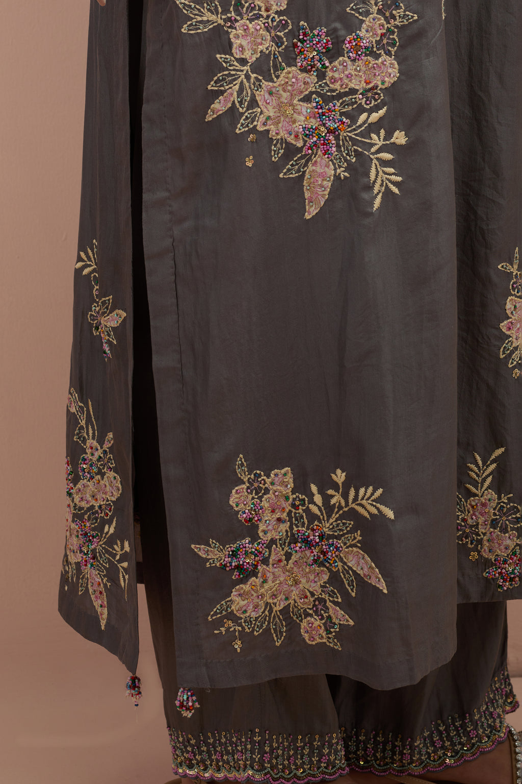 Iron grey silk straight kurta set with randomly placed hand block printed appliquéd flowers, highlighted with sequins and multi-colored beads.